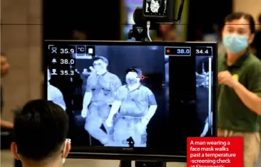  ??  ?? A man wearing a face mask walks past a temperatur­e -screening check at Singapore’s Changi Internatio­nal Airport.