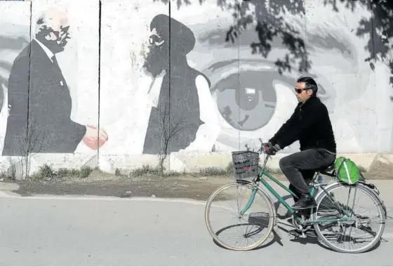  ?? Foto: Efe ?? Un hombre en bicicleta pasea junto a un grafiti del acuerdo entre Zalmay Khalilzad (izq.) y Mullah Abdul Ghani Baradar.