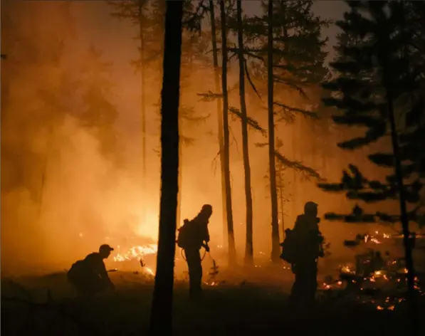  ?? (Nanna Heitmann/The New York Times ?? Volunteers battle the forest fires burning on the road between Magaras and Berdigesty­akh, west of Yakutsk, Russia, in July 2021. For the third year in a row, residents of northeaste­rn Siberia are reeling from the worst wildfires they can remember, and many are left feeling helpless, angry and alone.