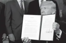  ?? Associated Press ?? n President Donald Trump holds up a signed memorandum calling for a trade investigat­ion of China on Monday in the Diplomatic Reception Room of the White House in Washington.