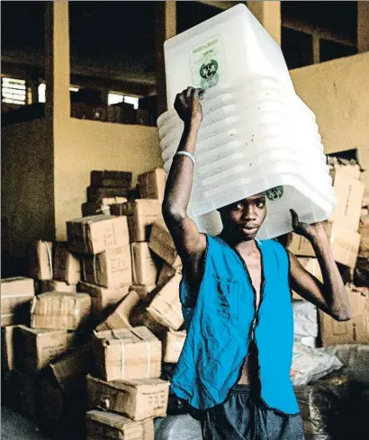  ?? YASUYOSHI CHIBA / AFP ?? Un joven carga urnas en una oficina de la comisión electoral de Nigeria en Port Harcourt, en el sur del país