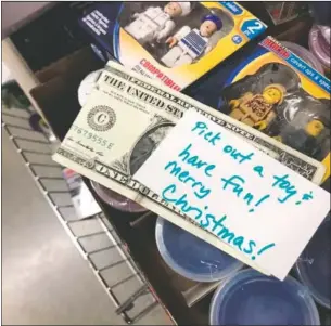  ?? (Courtesy Photo/Debbie McFarland) ?? A dollar bill and encouragin­g note, placed by McFarland, are seen in a bin of toys in a store in Peachtree City.