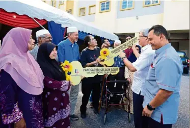  ??  ?? Giving a helping hand: ahmad Zakiyuddin (in white) and salem (right) handing over the mock keys of selasih Court apartments to villagers of Kampung mutiara in batu Feringghi.