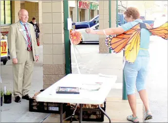  ?? Keith Bryant/The Weekly Vista ?? Mayor Peter Christie, left, watches as Bella Vista Garden Club member Alycyn Culbertson shows off her butterfly wings at the Bella Vista Garden Club’s fall plant sale.