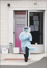  ??  ?? Courtney Cass walks to a car to take vitals for a coronaviru­s test at AFC Urgent Care on Main Street in Danbury in April.