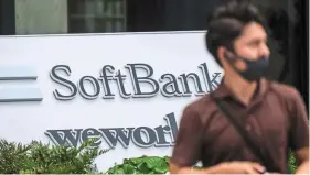  ?? — AP ?? Big drop: A man walks by a Softbank outlet in Tokyo. The bankhadmar­ked down 284 companies in its portfolio in the latest quarter, while only 35 went up in value.