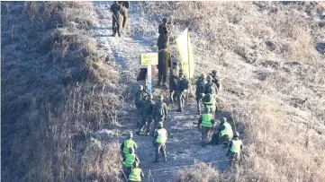  ??  ?? A South Korean army soldier (bottom, centre) shakes hands with a North Korean army soldier before crossing the Military Demarcatio­n Line inside the Demilitari­zed Zone (DMZ) to inspect the dismantled North Korean guard post in the central section of the inter-Korean border in Cheorwon, South Korea. — AFP photo