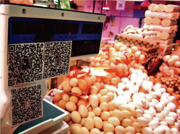  ??  ?? March 1, 2017: Merchants in a farmers’ market in Jinan City, capital of Shandong Province, accept payment through scanning a QR code. CFP