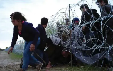  ?? BELA SZANDELSZK­Y/THE ASSOCIATED PRESS ?? Syrian refugees cross into Hungary underneath the border fence on the Hungarian-Serbian border.