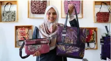  ?? ?? Wan Nur Akmal shows some of the exclusive batik bags produced by the PwD staff of Wakaf Tapai.