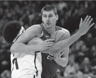  ?? Matthew Stockman, Getty Images ?? The Nuggets’ Nikola Jokic is tangled up while driving to the basket by Brooklyn’s Jarrett Allen during the first half of Friday night’s game at the Pepsi Center.