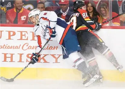  ?? ?? Washington Capitals’ Alex Ovechkin, left, withstands a hit by Calgary Flames’ Andrew Mangiapane during the first period of a game on Dec. 3.