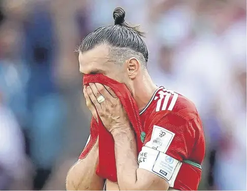  ?? ?? Captain Gareth Bale hides his face in his shirt following Wales’ 2-0 defeat by Iran at the World Cup in Qatar yesterday