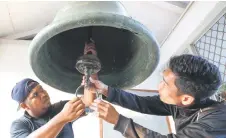  ?? — Bernama photo ?? Muizzuddin (right) and Muhammad Hamidi adjusting the clapper of the ‘genta’.