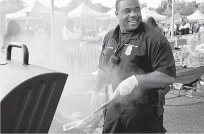  ?? KARL MERTON FERRON/BALTIMORE SUN PHOTOS ?? Officer Odis Daniels grills burgers at a National Night Out event at Mondawmin Mall on Tuesday.