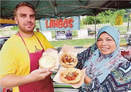  ?? PIC BY MUHAIZAN YAHYA ?? Adam Abdullah and Elsuraya Mohamed showing their lángos ‘sambal ikan bilis’, ‘sekaya’ power and chocolate ‘leleh’ at their stall in the compound of Toh Puan Besar Hatijah Mosque in Batu Gajah.