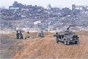  ?? TSAFRIR ABAYOV/THE ASSOCIATED PRESS ?? Israeli army vehicles and soldiers near the Gaza Strip border Saturday in southern Israel. The army is battling Palestinia­n militants across Gaza in the war ignited by Hamas’ Oct. 7 attack into Israel. The Health Ministry in Gaza on Saturday said 201 people had been killed over the past 24 hours.