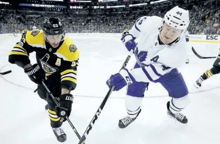  ?? MICHAEL DWYER/THE ASSOCIATED PRESS ?? Toronto Maple Leafs defenceman Morgan Rielly battles for the puck with Boston Bruins forward Brad Marchand during Saturday’s game in Boston. Rielly is on track this season to beat his personal best of 36 points.