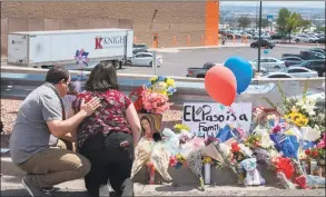 ?? Mark Ralston / AFP / Getty Images ?? People pray beside a makeshift memorial outside the Cielo Vista Mall WalMart, background, where a shooting left 20 people dead in El Paso, Texas, on Sunday.