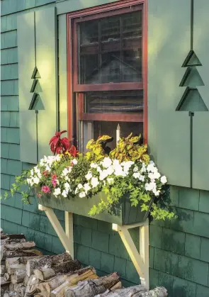  ??  ?? ABOVE Oversized brackets are part of a charming window dressing that include cutout cottage shutters. OPPOSITE (left) An upstairs box crowns a doorway arbor with built-in seats. (right) Simple hooks hold a long box below the rail, resting against...