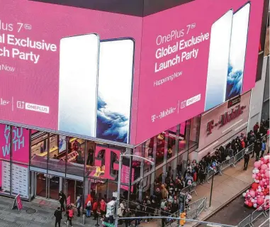  ?? Andrew Kelly / Associated Press ?? T-Mobile customers lined up outside the company’s store in New York’s Times Square are part of the wireless provider’s user base that combined with Sprint’s would total 125 million, making it second in size to AT&T.