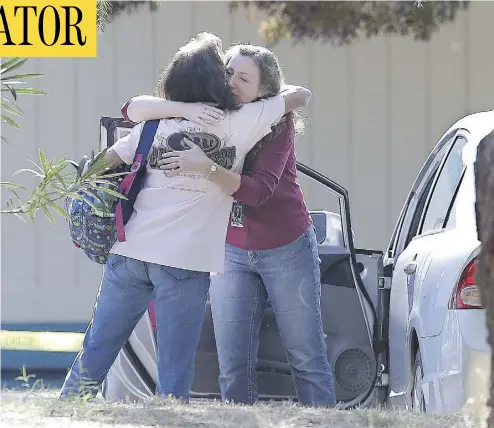  ?? RICH PEDRONCELL­I / THE ASSOCIATED PRESS ?? Two women embrace outside Rancho Tehama Elementary School in Corning, Calif., where a gunman opened fire. Police had no motive for the shooting, but said the shooter’s neighbours had reported a domestic violence incident.
