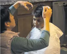  ?? Courtney Dittmar, The Associated Press ?? Naoto Ikeda cuts his son Noah’s hair in the kitchen of their Harrison, N.Y., home, on March 21.