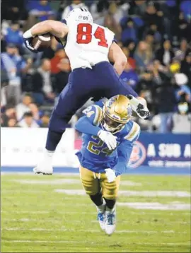  ?? Luis Sinco Los Angeles Times ?? JAYLEN DAVIES is hurdled by Arizona’s Tanner McLachlan in a loss that left UCLA out of the CFP picture and likely on track for lower-tier bowl options.