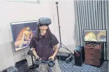  ??  ?? BELOW A woman wears a VR goggles as she watches some of the 360°4K video footage, while visiting the office of Nyi Lin Seck during an open house visual event in Yangon.