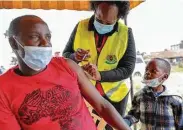  ?? Brian Inganga / Associated Press ?? A man receives a dose of AstraZenec­a vaccine donated by Britain as his son watches Saturday at the Makongeni Estate in Nairobi, Kenya.