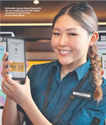  ?? ?? McDonald’s trainee Hwang Young with the new mobile app that will enables customers to earn rewards. Picture: Dean Martin