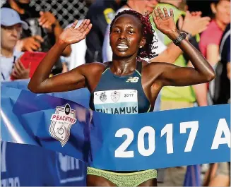  ?? CURTIS COMPTON/ CCOMPTON @AJC.COM ?? Aliphine Tuliamuk reaches the finish line in 32:49 and wins the women’s elite division of the AJC Peachtree Road Race, which served as the 10K national championsh­ip.