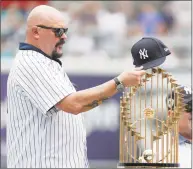  ?? Julio Cortez / Associated Press ?? Former Yankees pitcher David Wells puts his hat on the 1998 World Series trophy during a ceremony honoring the team prior to Saturday’s game.