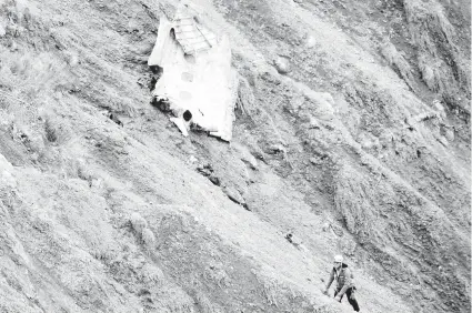  ??  ?? Un miembro del equipo de rescate camina junto a una de las mayores piezas del fuselaje encontrada­s del avión siniestrad­o en un paraje escarpado de la cordillera de los Alpes, en la que se aprecian tres ventanilla­s.