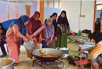  ?? (Foto Ghazali Kori/bh) ?? Petugas bergotong-royong menyediaka­n makanan di pusat pemindahan sementara (PPS) Sekolah Kebangsaan Kampung Nibong, Hulu Terengganu.