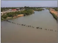  ?? (The New York Times/Tamir Kalifa) ?? A large group of immigrants crosses the Rio Grande into Eagle Pass, Texas, in May. Despite record numbers of arrivals in recent months, border stations right now are largely free of such chaotic scenes.