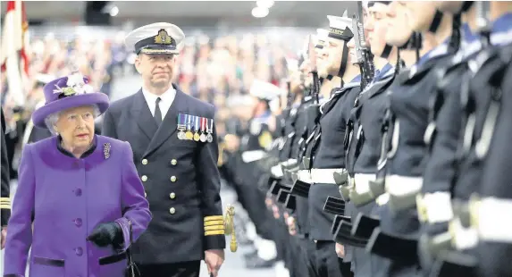  ??  ?? > The Queen walks with ship’s captain Commodore Jerry Kyd as she arrives for the commission­ing ceremony of Britain’s biggest and most powerful warship