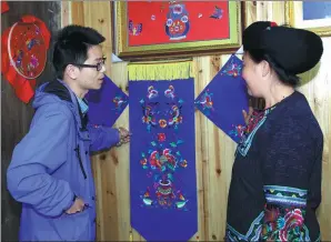  ?? WU HONGYAN / FOR CHINA DAILY ?? Liu Xiangrui speaks with a member of a Miao embroidery and dress cooperativ­e in Huayan, Hunan