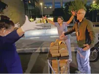  ?? JEFF CHIU/ASSOCIATED PRESS ?? Nightbird Restaurant chef and owner Kim Alter, left, mimicks giving a hug to nurse practition­er Sydney Gressel, center, and patient care technician Matt Phillips after delivering dinner to them March 27 at the University of California at San Francisco Benioff Children’s Hospital in San Francisco.