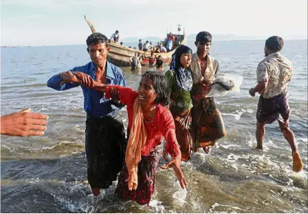  ??  ?? Harrowing journey: Rohingya refugees being helped after arriving by a wooden boat from Myanmar to the shore of Shah Porir Dwip in Teknaf, near Cox’s Bazar, Bangladesh. — Reuters