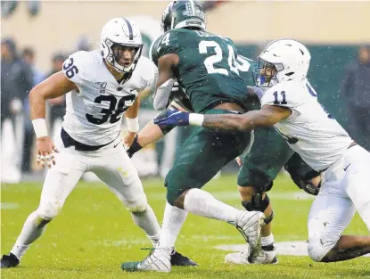  ?? DUANE BURLESON/GETTY ?? Michigan State running back Elijah Collins is tackled by Penn State linebacker­s Micah Parsons, right, and Jan Johnson during the first half Saturday at Spartan Stadium. The Nittany Lions defense held the Spartans to 83 yards rushing.