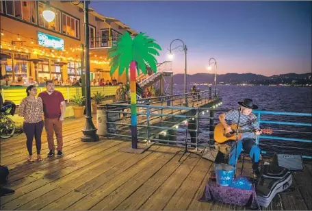  ?? Photograph­s by Allen J. Schaben Los Angeles Times ?? STREET PERFORMER Robert Roadawg, right, plays classic rock songs on the Santa Monica Pier after winning a coveted lottery space.