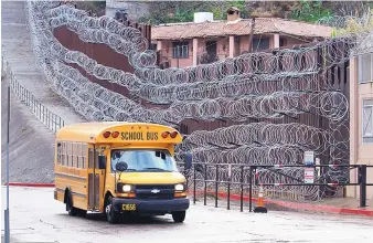  ?? JONATHAN CLARK/NOGALES INTERNATIO­NAL ?? A school bus rolls past the concertina wire-covered fence at East Internatio­nal and Nelson Streets in downtown Nogales, Ariz., Monday.