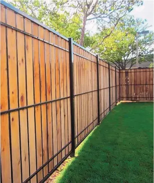  ?? COURTESY OF ABQ FENCE ?? Vertical wood and iron fences help add privacy to a yard.