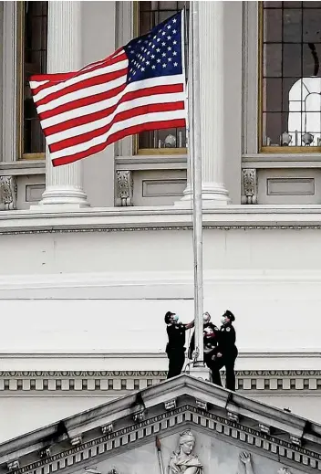 ?? Joe Raedle / Getty Images ?? Old Glory is lowered to half-staff on the Capitol following the death of Brian D. Sicknick, a Capitol Police officer. He was fatally injured when a pro-president Donald Trump mob stormed into the building.