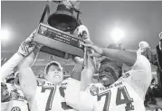  ?? Stacy Revere / Getty Images ?? Joseph Cheek, left, and Germain Ifedi hoist the trophy after A&M won the 2014 Liberty Bowl.