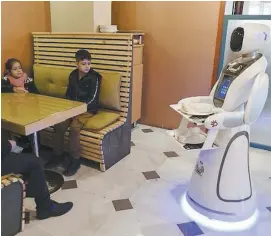  ?? PHOTO AFP ?? Les clients peuvent passer des commandes via un écran tactile placé sur le ventre de Timea qui les transporte jusqu’aux tables.