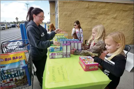  ?? NWA Democrat-Gazette/BEN GOFF @NWABENGOFF ?? Janell Taylor (from left) of Elm Springs buys Girl Scout Cookies from Emma Griggs, Caroline Barnett and Olivia Tingley last month when Brownie Troop 5343 held a sale outside the Wal-Mart Supercente­r on Elm Springs Road in Springdale. The troop plans to...