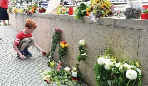  ??  ?? Kerstin Joensson / Associated Press Above, a boy puts down flowers Saturday near a mall where a shooting took place leaving nine people dead the day before in Munich. The rampage was the third mass attack in a week in Europe, after the Nice attack and...