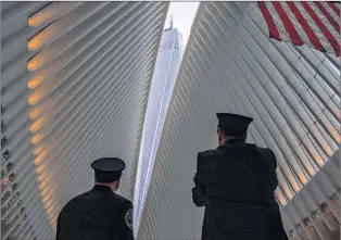  ?? AP PHOTO ?? Two members of the New York City fire department look towards One World Trade Center through the open ceiling of the Oculus, part of the World Trade Center transporta­tion hub in New York Tuesday, the anniversar­y of 9/11 terrorist attacks. The transit hall ceiling window was opened just before 10:28 a.m., marking the moment that the North Tower of the World Trade Center collapsed on September 11, 2001.